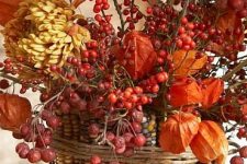 a vase covered with corn cobs, dried blooms, berries and soem twine is a bold centerpiece for fall or Thanksgiving