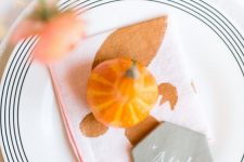 a very simple and lovely Thanksgiving place setting with a white and striped plate, a printed napkin, a gourd and a marble card