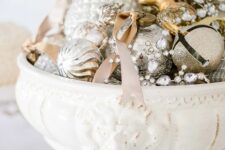 a vintage white bowl with mercury glass, silver and gold ornaments and rhinestones is a vintage Christmas centerpiece