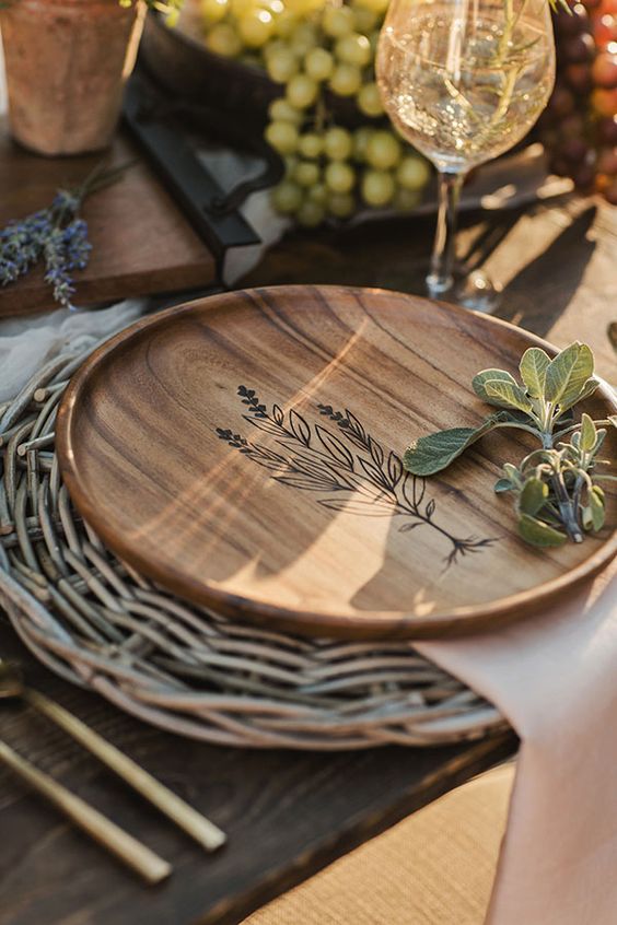 A woven placemat and a wooden plate with wood burning for a lovely farmhouse inspired Thanksgiving tablescape