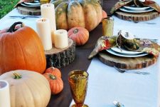 an all-natural Thanksgiving tablescape with tree stumps, heirloom pumpkins, candles, bright printed napkins and colored glasses