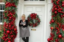 an amazing home entrance with evergreen garlands and red ornaments, pinecones and a matching wreath on the door for Christmas