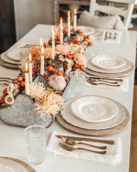 An eye catchy Thanksgiving centerpiece of a metal tool box with blush and white blooms, berries and tall and thin candles