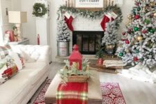 bright and fun Christmas decor with a flocked tree with gold, green and red ornaments, plaid pillows and a runner, red stockings, a flocked garland and flocked mini trees