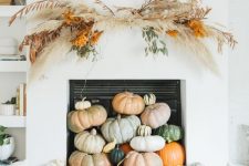 heirloom pumpkins stacked in the fireplace, a dried grass overhead installation and some firewood for fall and Thanksgiving