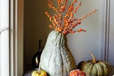 heirloom pumpkins with blooms and an oversized gourd with berried branches is a lovely all-natural decoration