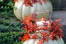 large white pumpkins with pillar candles in the center, with vines and bold leaves are amazing for decorating both indoor and outdoor spaces