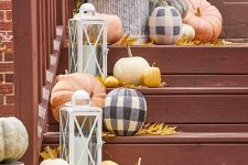 neutral and plaid pumpkins, bright leaves, candle lanterns and white blooms in a pot for decorating outdoors