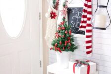 red and white ornaments in a wire bucket, red ornaments for a tiny tree and white stockings create beautiful Christmas entryway decor