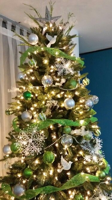 a Christmas tree with silver, clear and green ornaments, green ribbons, snowflakes and birds plus a star topper