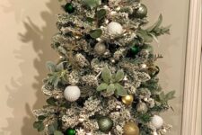 a Christmas tree with white, green and gold ornaments, lights and foliage looks gorgeous and chic