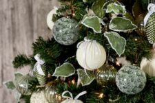 a beautiful green Christmas tree with white, gold and green patterned ornaments, leaves, lights and ribbons is a chic decoration