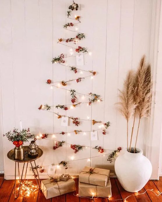 A boho wall mounted Christmas tree of lights, berries and Christmas cards plus pampas grass and blooms around
