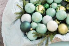 a bowl with pastel green paper, pastel green and dark green ornaments, evergreens is a lovely decoration or a centerpiece