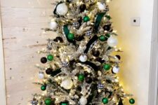 a cool farmhouse flocked Christmas tree decorated with black, emerald and white ornaments, lights, branches and buffalo check ribbons