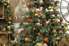 a fabulous woodland glam Christmas tree with copper, orange, light green ornaents, pinecones, vines and vine decorations is amazing