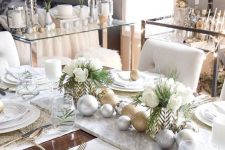 a glam and elegant Christmas tablescape with gold glitter and silver ornaments, gold placemats, white blooms and greenery and elegant white plates