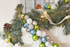 a green, white and blue Christmas ornament garland over the fireplace for cool holiday decor