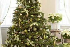 a large Christmas tree decorated with light green and silver ornaments, silver beads and light green bows plsu green gift boxes under the tree