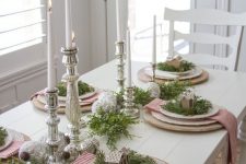 a merry Christmas table with mercury glass candleholders and ornaments, wooden placemats, red and white striped napkins and gingerbread houses