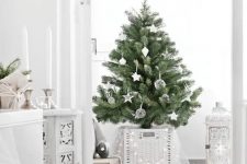 a modern Scandi Christmas tree with white and clear ornaments, lights hanging on the basket and some tulle is a chic odea
