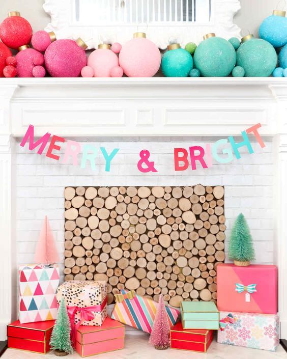A non traditional and bold Christmas mantel with large and small color block Christmas ornaments, a matching letter banner and gift boxes