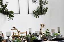 a pretty glam Christmas tablescape with black plates and bowls, smoked glasses, black napkins, gold deer and lots of fresh greenery