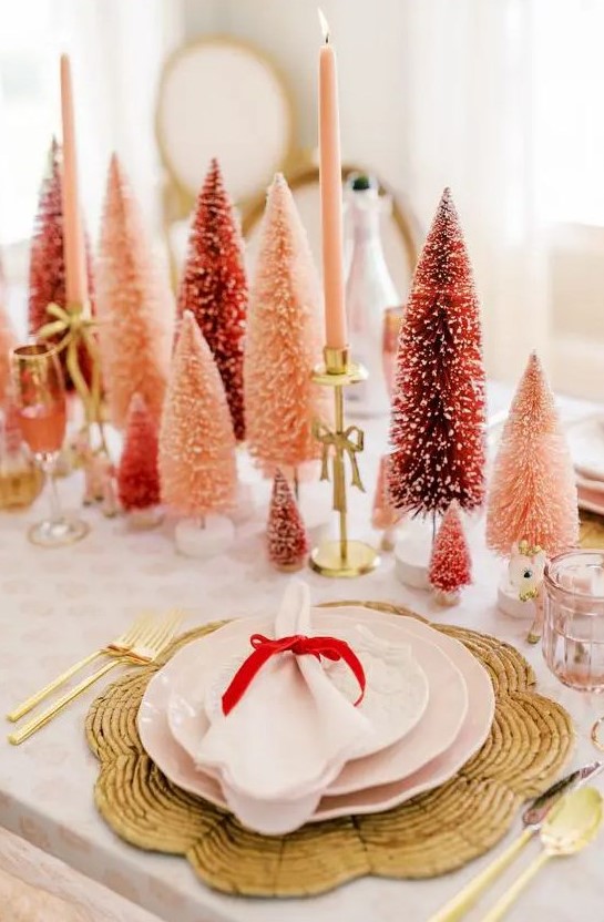 a sophisticated Christmas tablescape with red and pink bottle brush trees, pink candles, woven placemats and pink porcelain