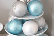 a stand with silver and blue glitter Christmas ornaments is a nice centerpiece or some other decoration
