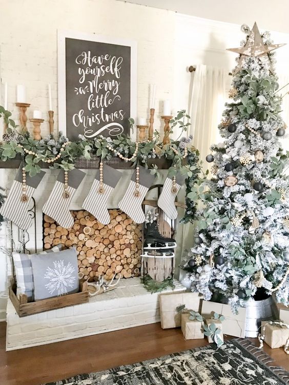 a vintage rustic Christmas mantel with a fresh greenery garland, wooden beads, striped stockings and lanterns in wooden candleholders