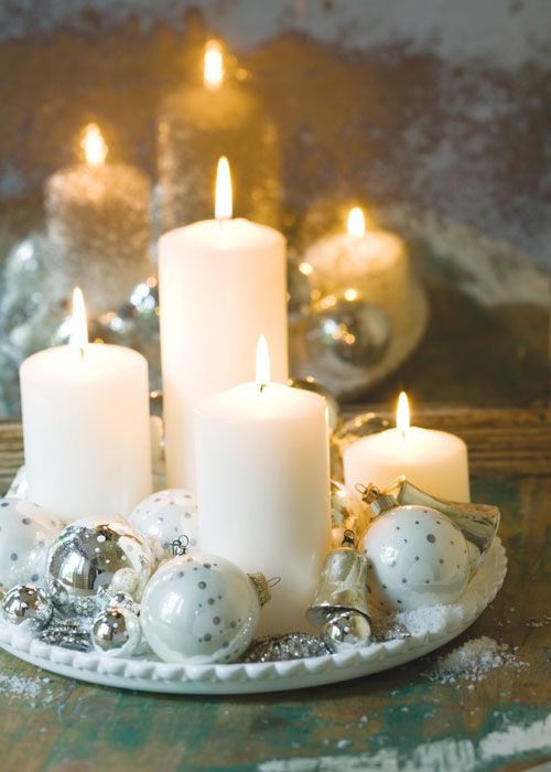 a white tray with white and silver Christmas ornaments and pillar candles plus faux snow is a gorgeous centerpiece