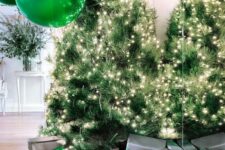 gorgeous Christmas decor with lots of lit up Christmas trees, emerald balloons and grey and green gift boxes is wow