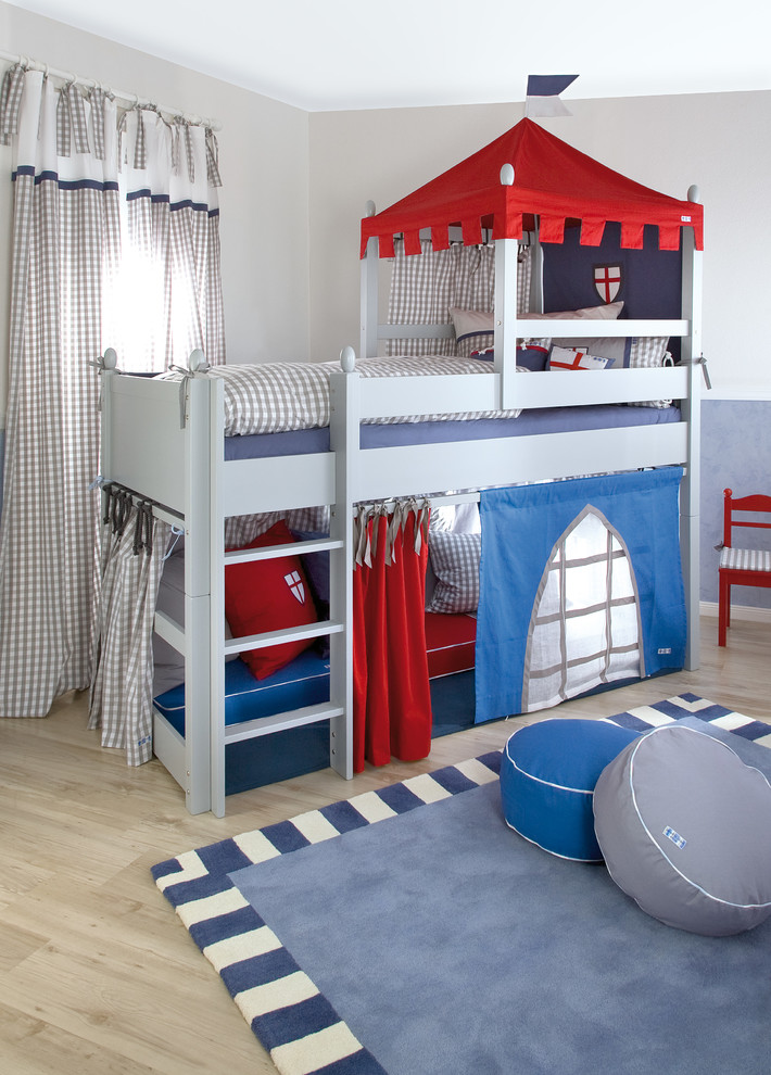 This boys bedroom in nice grey, blue and red tones doubles as a fun playroom.