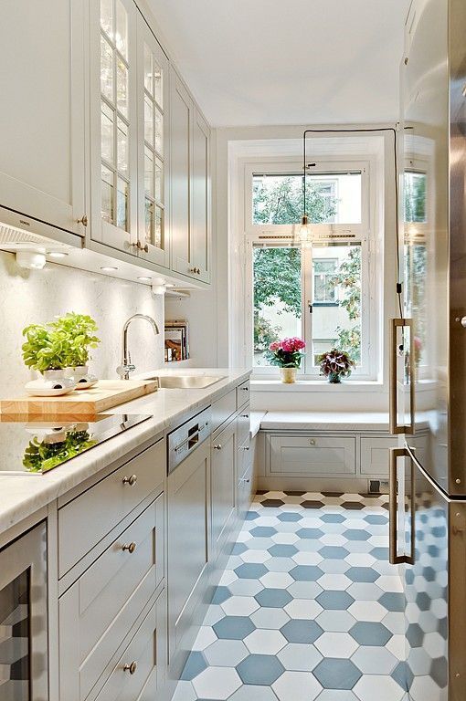 a beautiful white kitchen with white countertops, a white backsplash, a hex tile floor and a windowsill bench