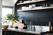 a black kitchen with contrasting light-colored shelves, handles and countertops plus a burlap pendant lamp