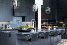 a black kitchen with textural cabinets, a kitchen island with a stone countertop and woven stools plus pendant lamps