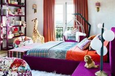 a bright bedroom with a purple bed and nightstnads, a purple storage unit, a floral pouf, orange curtains and a colorful pendant lamp