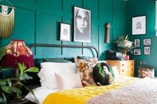 a colorful bedroom with emerald walls, a metal bed, a yellow dresser, bold bedding, potted plants and a macrame hanging
