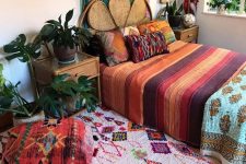 a colorful boho bedroom with bold textiles, pillows, rugs, ottomans and a bunting artwork on the wall is a fun space