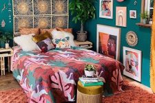 a colorful boho bedroom with green walls, a bed with a woven headboard, colorful textiles and a bold gallery wall plus statement plants