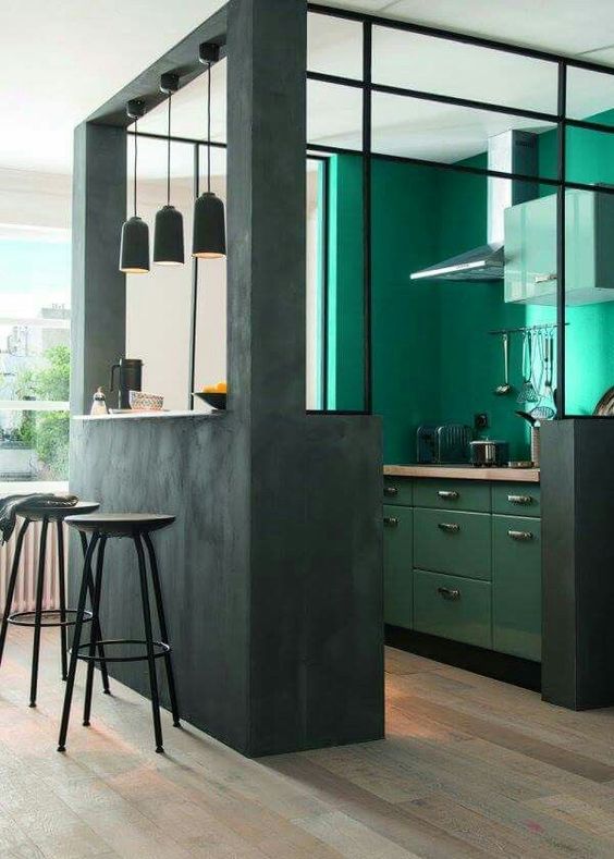 a dark green kitchen cube with emerald walls and cabinets inside, butcherblock countertops and pendant lamps