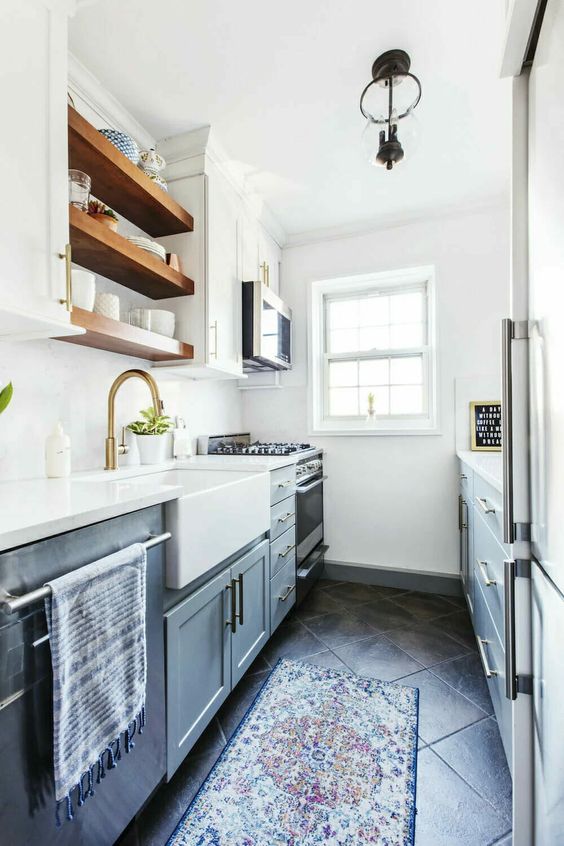 a grey and white kitchen with open shelves, gold touches and printed rugs is a cool space