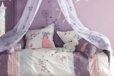 a lovely purple girl’s room with floral murals, a white bed with purple and neutral bedding, a cool rug and a cushion