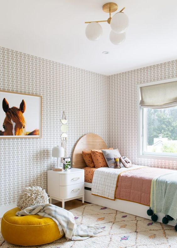 A mid century modern girl's room with a white and stained bed with bold bedding, printed wallpaper, a horse artwork, a mustard cushion and a creamy nightstand