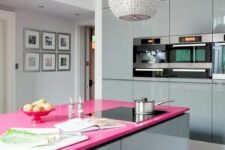 a minimalist glam kitchen done with shiny grey glossy cabinets, a hot pink kitchen island countertop and a shiny embellished pendant lamp