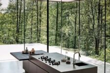 a minimalist grey kitchen with stone coutnertops and an additional built-in mini table plus glazed walls to feel like in the forest