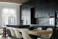 a minimalist kitchen with black cabinets, a marble backsplash, a two-part kitchen island and rough wooden beams