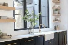 a modern farmhouse kitchen with black shaker cabinets, white countertops and statement flaoting shelves plus black and gold sconces