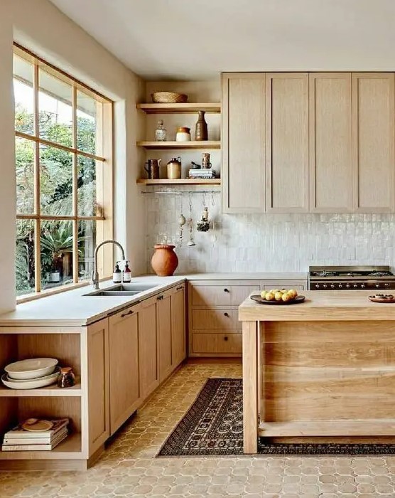 A natural looking kitchen with light stained cabinets, a white Zellige tile backsplash, white stone countertops, open shelves and a wooden kitchen island