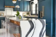 a navy kitchen with brass handles and pendant lamps, a fantastic waterfall kitchen island in black and white and striped stools